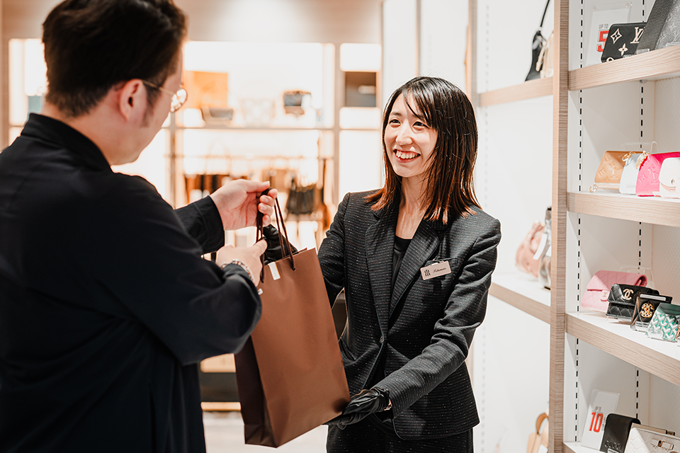 来店したお客様へ商品を手渡すスタッフの写真